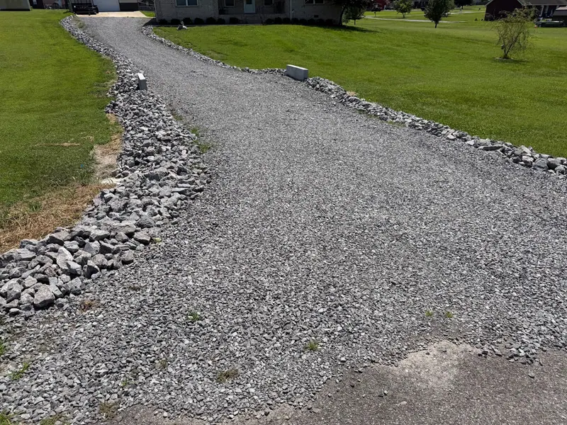 New gravel driveway with rock-lined edges curving up to a house