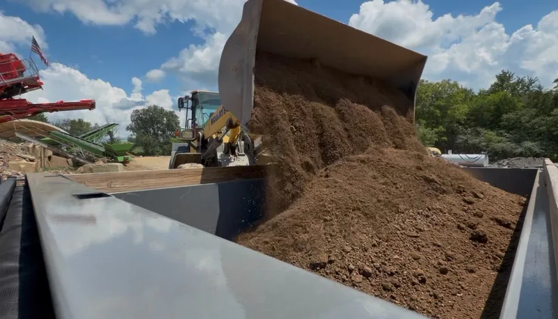 Wheel loader tipping a bucket of soil into a dump trailer